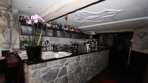 A bar area with a stone counter, shelves of liquor bottles, and a potted orchid. - Pension Villa Colosseo (Meiningen)