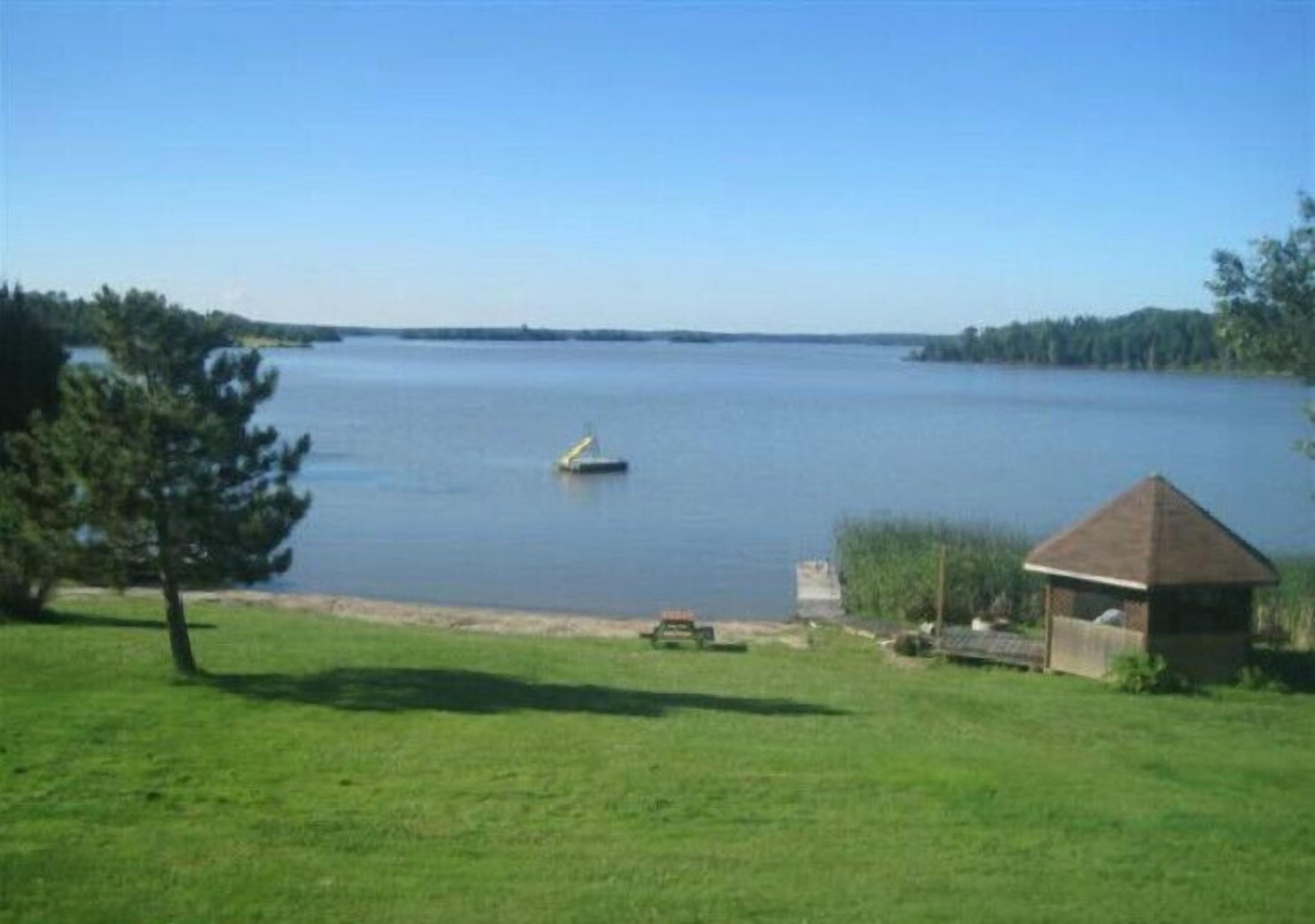Una propiedad frente al lago con un muelle pequeño, una mesa de picnic y un pabellón.