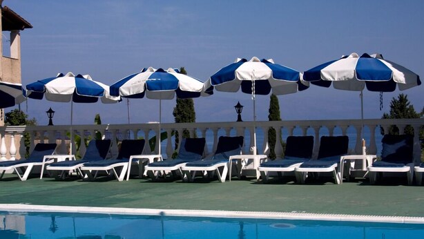 A poolside area with lounge chairs and umbrellas. - Sea view Apartment P/4 (Benitses, Corfu)