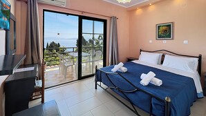 A bedroom with a bed, a desk, and a view of the outdoors. - Sea view Apartment P/4 (Benitses, Corfu)