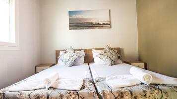 A double bed with floral bedding, two pillows, and rolled towels.