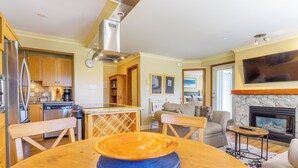 Eine moderne Küche mit Edelstahlgeräten, ein Essbereich mit Holztisch und ein Wohnzimmer mit Kamin.