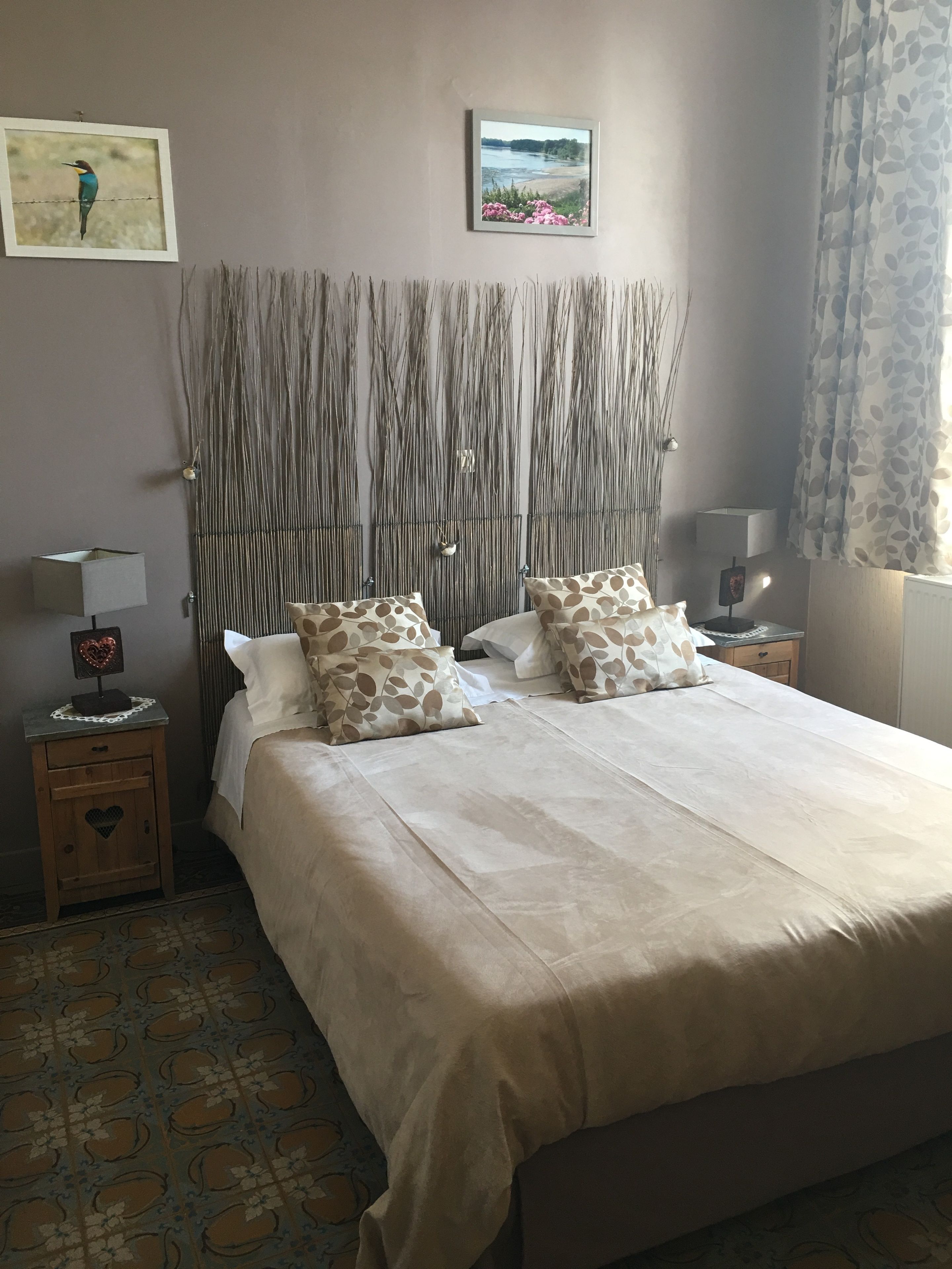 Ein Schlafzimmer mit einem großen Bett, zwei Nachttischen, einer Wandleuchte und einem gerahmten Bild über dem Bett.