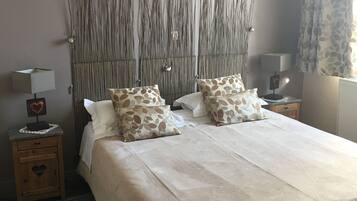 Un dormitorio con una cama grande, dos mesitas de noche, una lámpara de pared y un cuadro enmarcado sobre la cama.