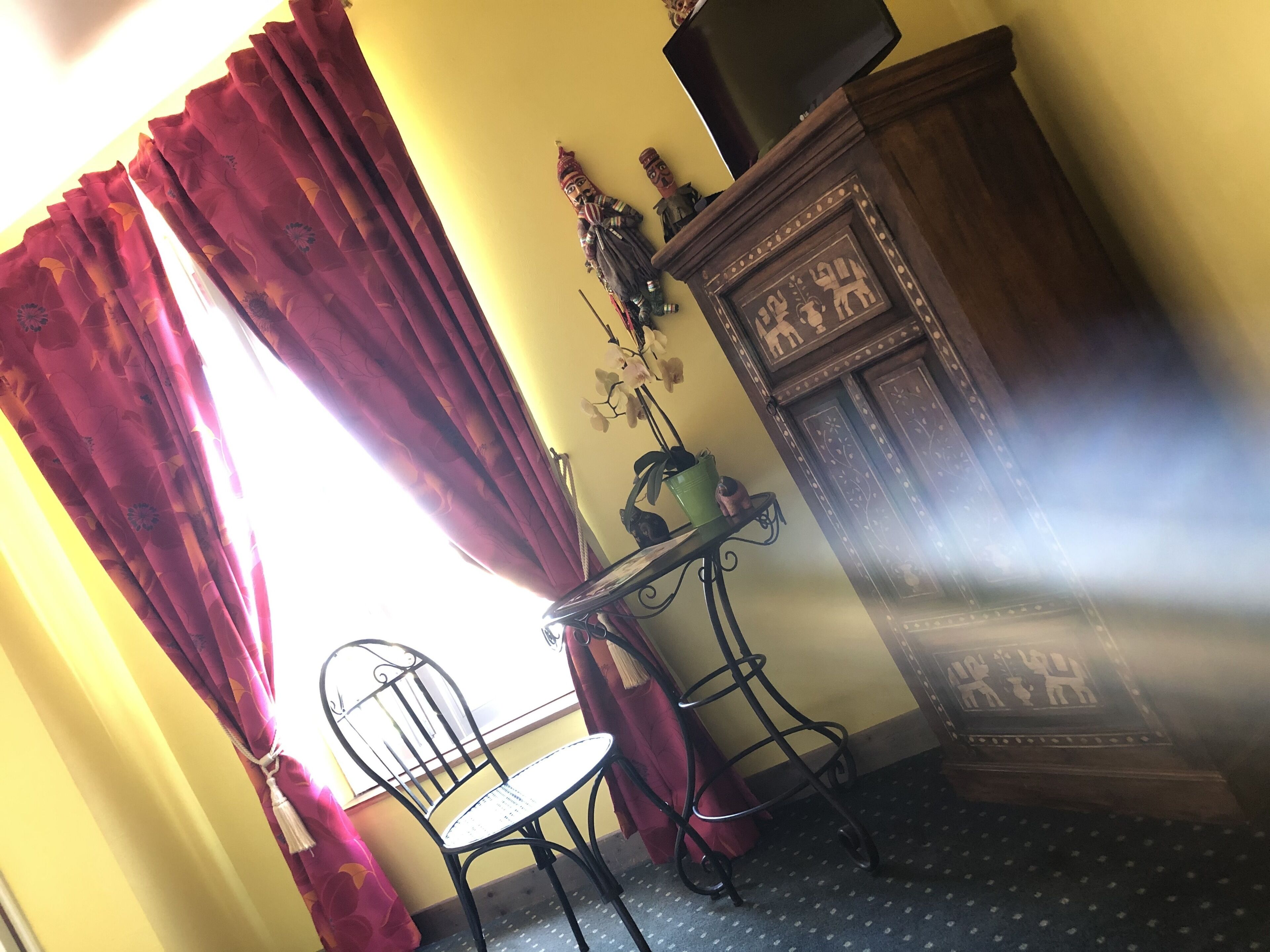 A room with a chair, a small table, a cabinet, and a window with curtains.