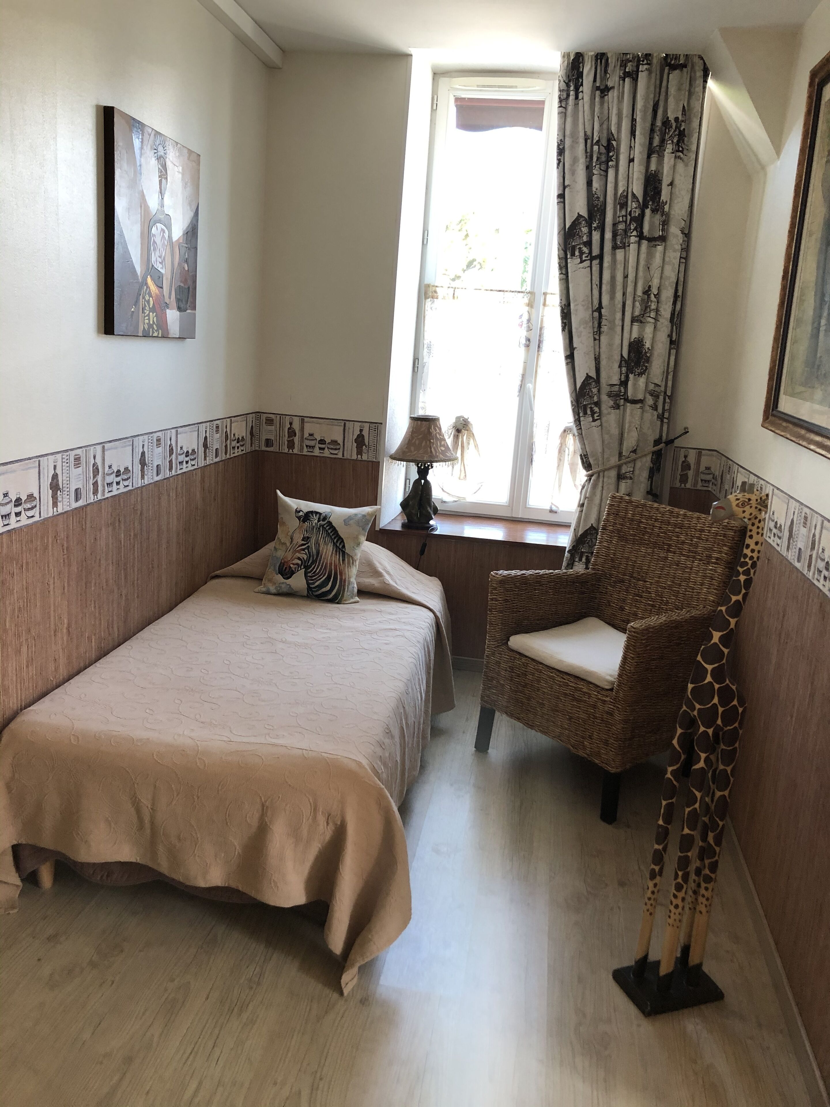 A bedroom with a bed, a chair, a lamp, and a window with curtains.