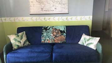 A blue sofa with tropical-themed cushions and a map on the wall above.
