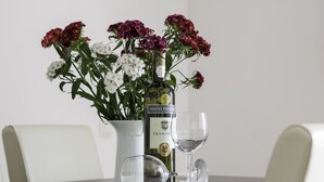 A table with a bottle of Traminum wine, two wine glasses, and a vase with flowers. - 2 Bedroom, 4 Guests, Direct on a stunning beach (Mimice)