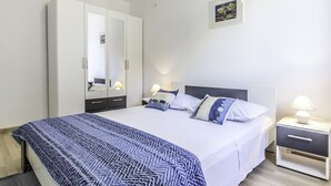 A bedroom with a bed, bedside tables, a wardrobe, and a painting on the wall. - 2 Bedroom, 4 Guests, Direct on a stunning beach (Mimice)