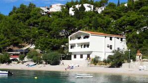 A coastal building with a balcony, situated near a beach with boats and people. - 2 Bedroom, 4 Guests, Direct on a stunning beach (Mimice)