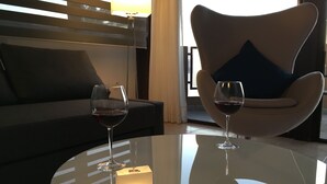 A modern room with a glass table, two wine glasses, a sofa, and a chair with a pillow. - Apartment PANORAMA Great View, WiFi, 50m beach (Costa Calma)