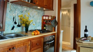 A kitchen with a tiled backsplash, wooden cabinets, a stainless steel sink, and a stove. - Apartment in residence with panoramic sea view terrace SEA VIEW (Santa Maria Navarrese)