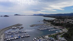 A marina with numerous boats docked, surrounded by a coastal town and mountains in the background. - Apartment in residence with panoramic sea view terrace SEA VIEW (Santa Maria Navarrese)