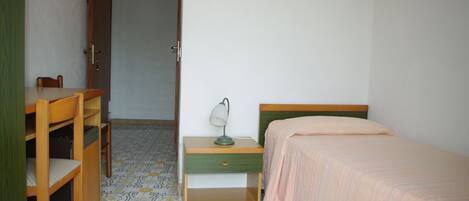 Un dormitorio con cama, mesita de noche, escritorio y silla.