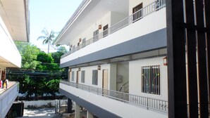 Un edificio de varios pisos con balcones, una escalera y vistas al verdor.