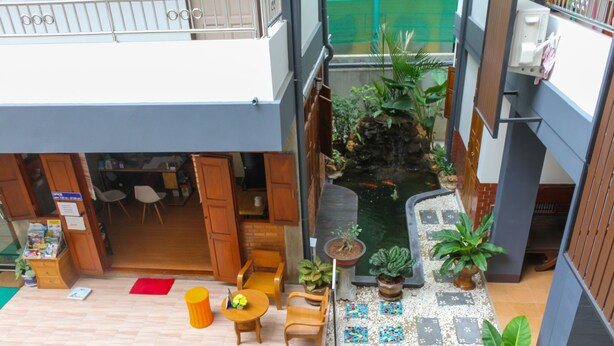 Un patio interior con zona de estar, plantas en macetas y un pequeño estanque.