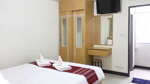 Una habitación de hotel con cama, armario, espejo, televisor y baño.