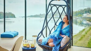 A person relaxing in a hanging chair with a view of a lake and buildings. - Ice House Hotel (Ballina)