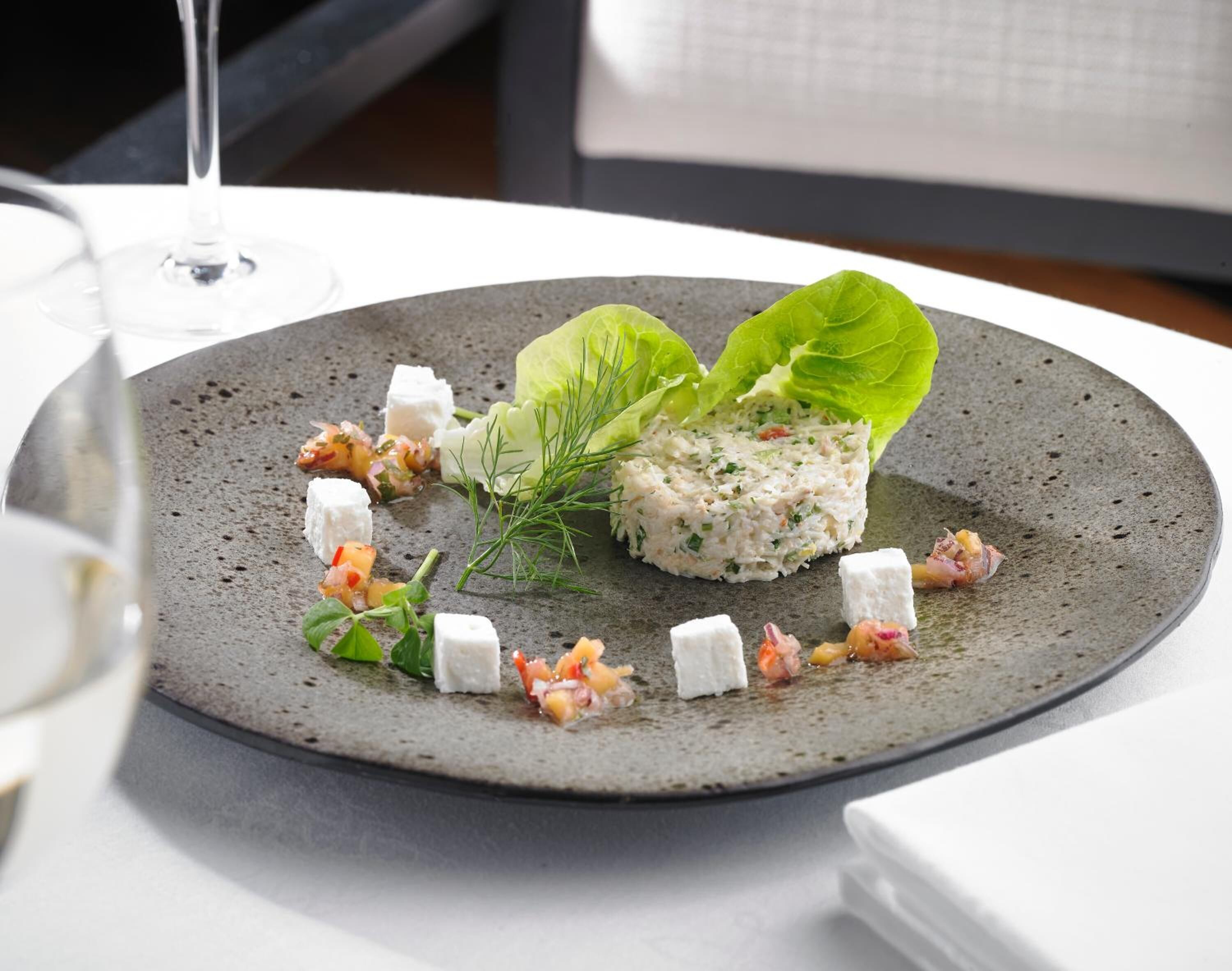 A plate of food with a salad, cheese, and a drink on the table.