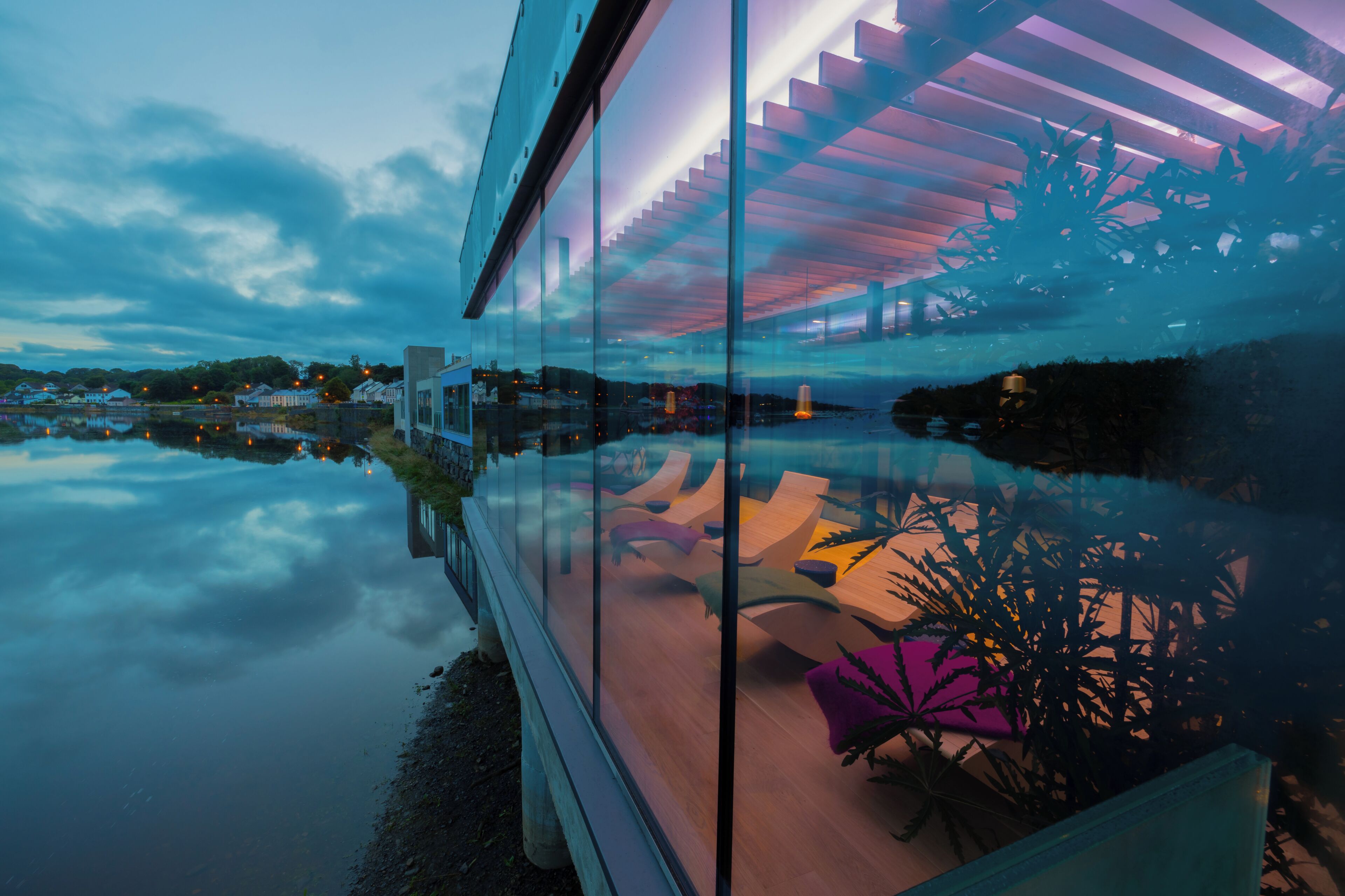 A modern building with a glass facade reflecting the sky and surrounding landscape.