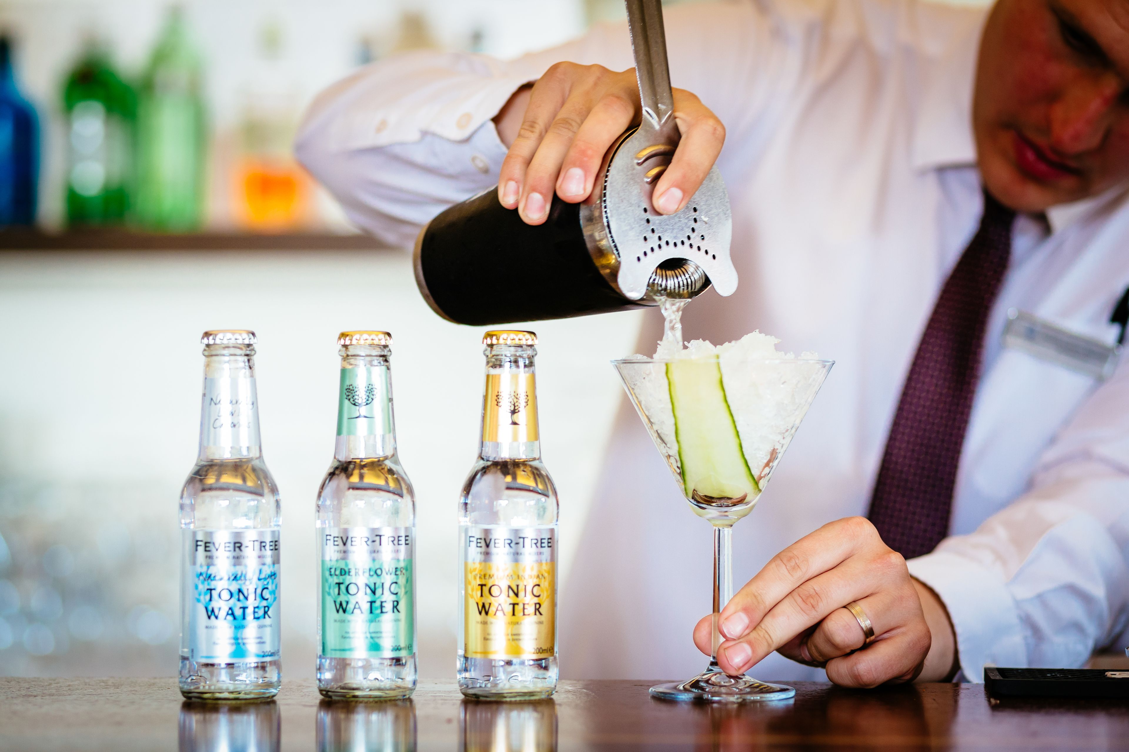 A bartender pouring a drink into a martini glass.