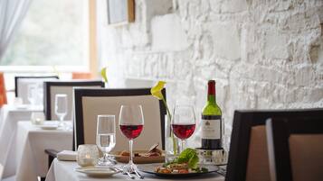 A dining table set with wine glasses, a bottle of wine, and a salad.