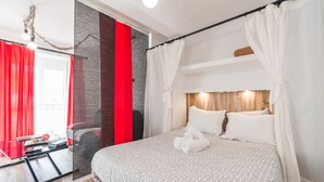 Ein modernes Hotelzimmer mit einem Bett, einem Glastisch und einem roten Vorhang.
