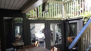 En uteservering med träbord och stolar, en trappa och utsikt över gatan.