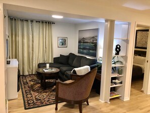 A living room with a sofa, a chair, a coffee table, and a bookshelf.