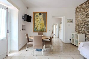 Une chambre moderne avec un coin repas, un mur en pierre et un tableau représentant une femme.