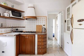 A compact kitchen with a stove, microwave, and a refrigerator.