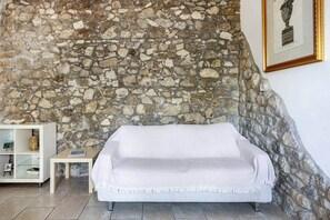 Ein Zimmer mit Stehwänden, einem weißen Sofa, einem kleinen Tisch und einer weißen Kommode mit Dekoration.