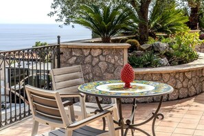 A patio with a table and chairs, a decorative pineapple centerpiece, and a view of the sea.