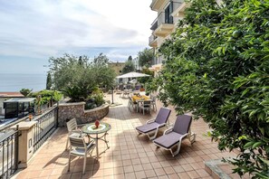 Une terrasse avec des sièges extérieurs, une table et une vue sur la mer.