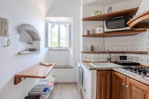 Eine kleine Küche mit Fenster, Mikrowelle, Herd und Spüle.