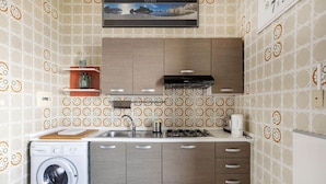 Una cocina compacta con lavadora, fregadero, cocina y cafetera.