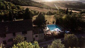 Una villa con piscina, rodeada de exuberante vegetación y colinas.