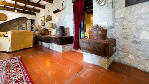 Un interior rústico de piedra con techo de madera, un sofá, barriles y una cortina roja.