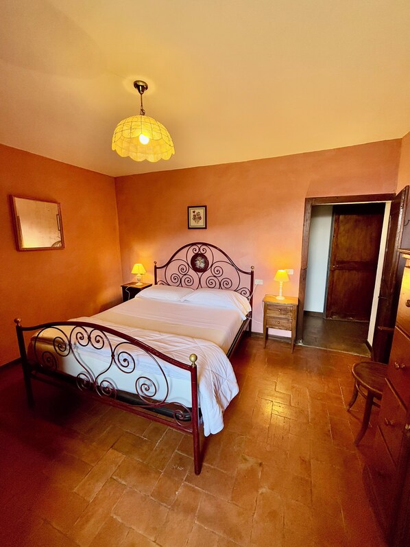 A bedroom with a bed, two bedside tables with lamps, a mirror, and a door.