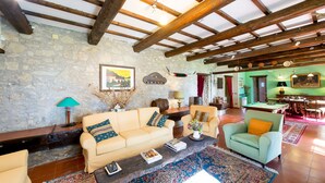 Un salón amplio con pared de piedra, vigas de madera, una mesa de billar y una pared verde con un cuadro.