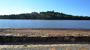 A coastal view with a stone wall in the foreground and a hill with buildings in the background. - Icarai Palace Hotel e Pousada (Poços de Caldas)
