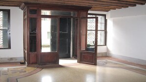 A room with a wooden door, a window with decorative iron bars, and a tiled floor.