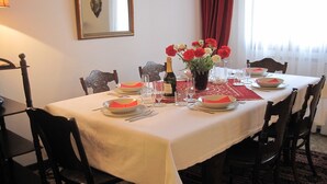 A dining table set with plates, cutlery, glasses, a bottle of wine, and a vase with flowers.