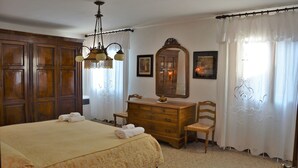 A bedroom with a large bed, wooden dresser, and a mirror.