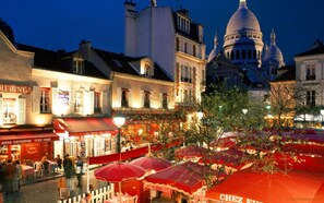 A bustling street scene with historic buildings and a prominent dome structure in the background.
