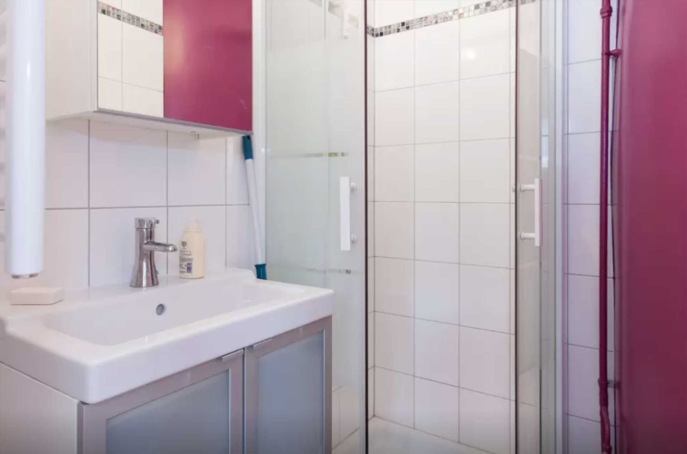 A bathroom with a white sink, a mirror, and a glass shower enclosure.
