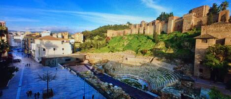 A historical site with ancient ruins, a central open space, and surrounding buildings.