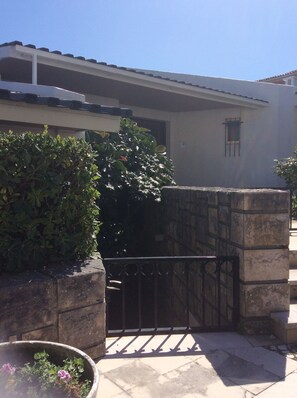 A gated entrance with a stone wall, a metal gate, and a potted plant with flowers.