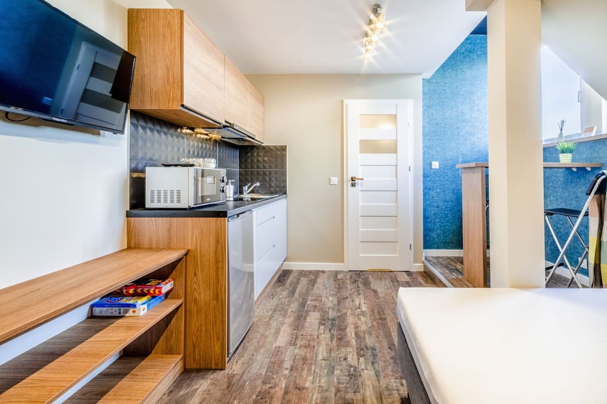 A compact kitchen with wooden cabinets, a microwave, and a built-in dishwasher.