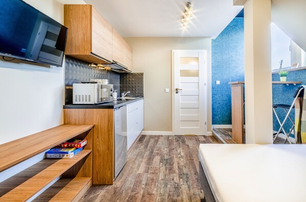 A compact kitchen with wooden cabinets, a microwave, and a built-in dishwasher.
